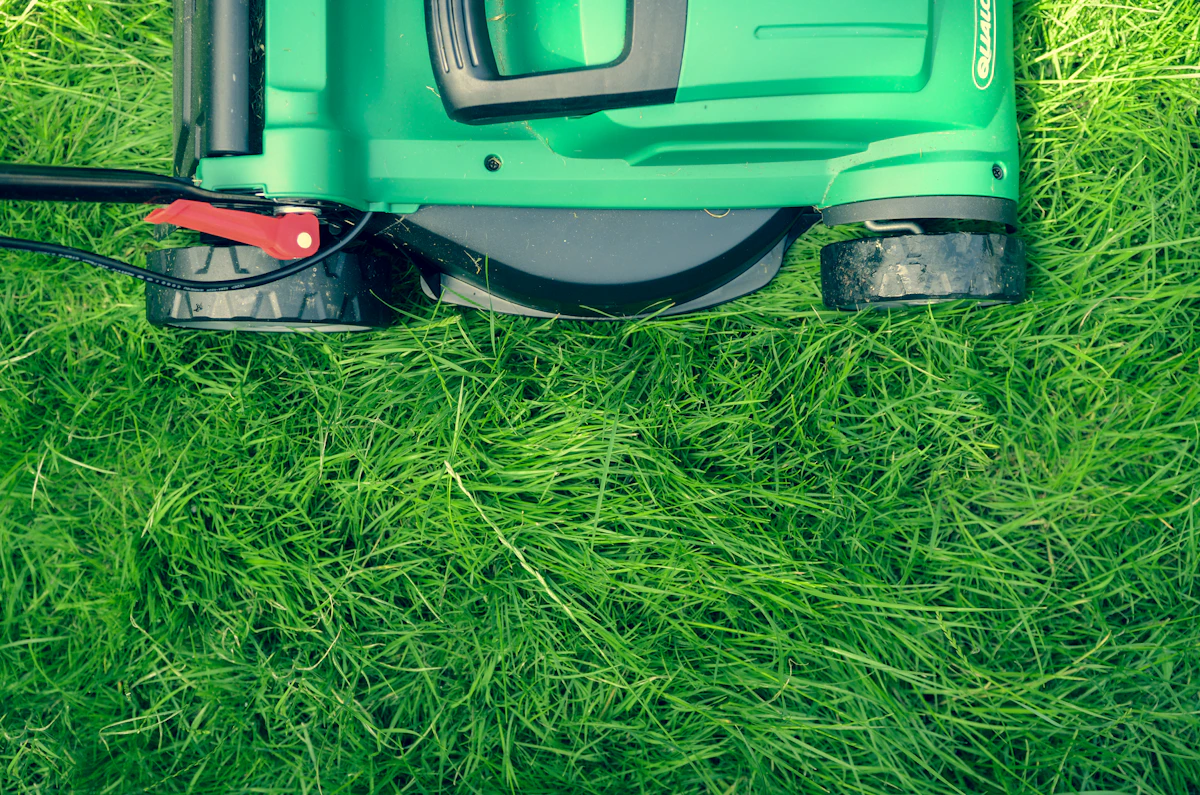Close view of a lawn mower cutting a bright green lawn